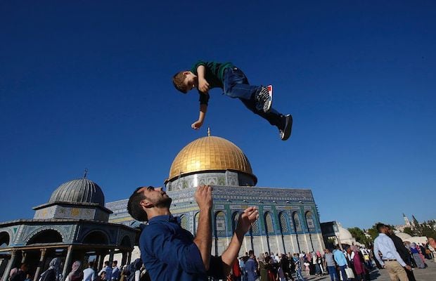 A Palestinian man plays with a kid outside the Dome of the Rock in Jerusalem's Al-Aqsa mosque compound following Eid prayers.